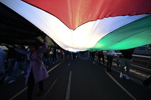 Protestors carry an extra large Palestinian flag together at a rally in Milan, Italy.