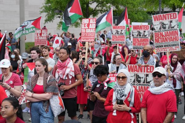 Protestors in Washington DC against Israel's genocide in Gaza carry signs that say "END ALL U.S. AID TO ISRAEL: STOP THE GENOCIDE #ShutItDownForPalestine" AND "WANTED: WAR CRIMINAL BENJAMIN NETANYAHU, FOR CRIMES AGAINST HUMANITY, KNOWN WHEREABOUTS: US CAPITOL - DC - JULY, 24, 2024."