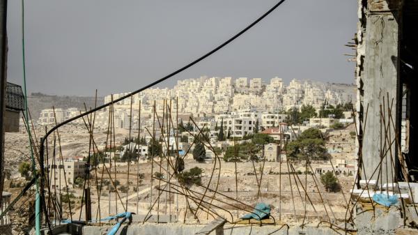View of an Israeli settlement in the West Bank through pieces of reinforcement steel.