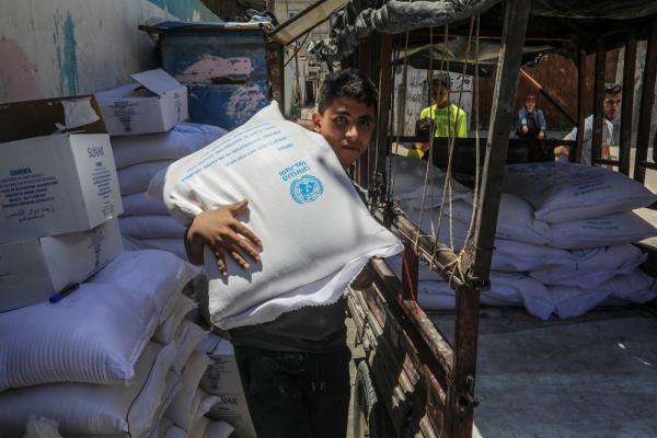 A young Palestinian carries an UNRWA food aid package from their distribution center in the Rafah refugee camp. May 22, 2022.