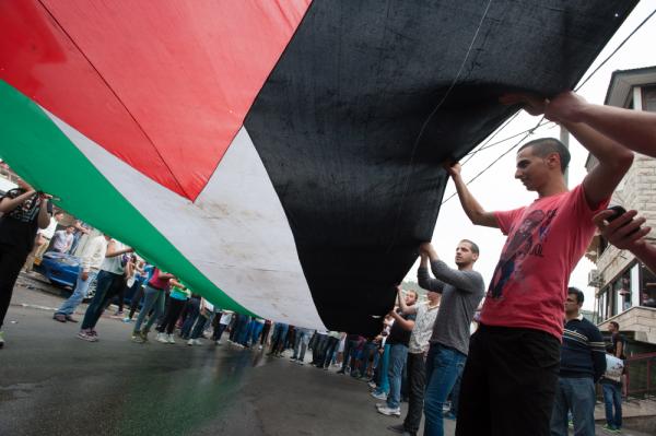Palestinian citizens of Israel participate in a Land Day protest in Sakhnin, a town in the Galilee in 2013, carrying an extra-large Palestinian flag together.