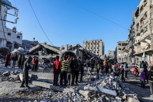 Palestinians view the damage of Al-Farouq Mosque and nearby homes, many children stand by. February 2024.
