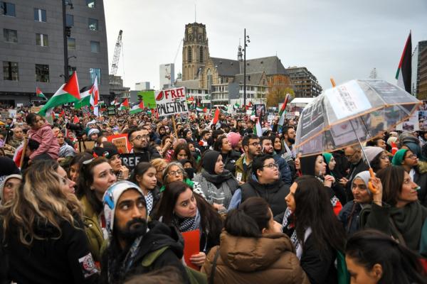 Large crowd, many wearing kuffiyehs, carrying signs, and waving Palestinian flags during a protest against Israel's war on Gaza in Rotterdam, Netherlands. November 19, 2023.