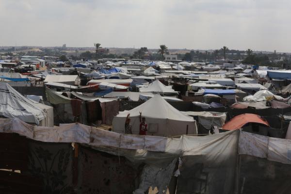 Two displaced Palestinians in the overcrowded, makeshift refugee camp in Khan Yunis, surrounded by tents.
