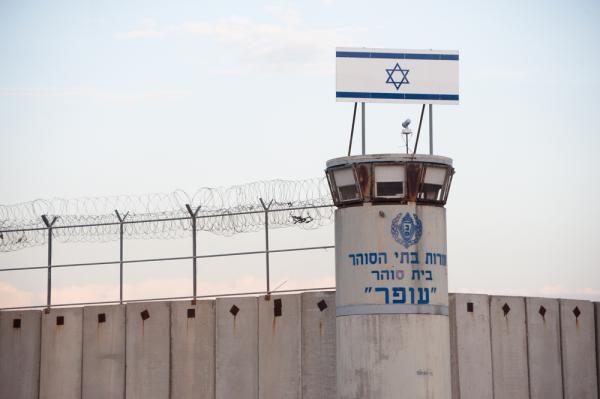 A view of the watchtower outside of Israel's Ofer military prison in the West Bank, with Hebrew writing and an Israeli flag sign at the top.