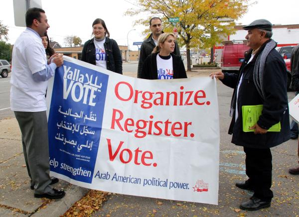 Arab Americans carry an AAI banner that reads "Yalla Vote: Organize. Register. Vote. Help Strengthen Arab American political power."