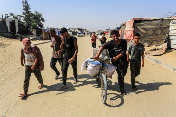 Palestinians carry aid from a GHF distribution site in Gaza.