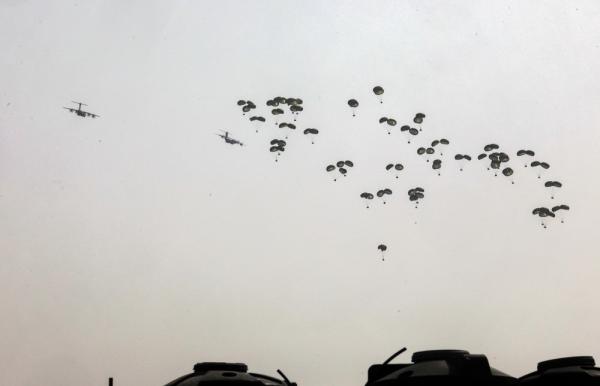 Ground-level view of an aid airdrop over Gaza, a method critiqued as ineffective and dangerous.