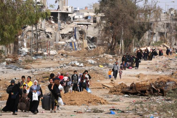 Displaced Palestinians walk along the bombed-out Salah al-Din Street in Gaza City's Zeitoun District carrying their belongings.