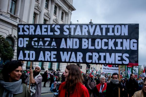 Protestors at a rally in London carry a sign that reads "ISRAEL'S STARVATION OF GAZA AND BLOCKING AID ARE WAR CRIMES."