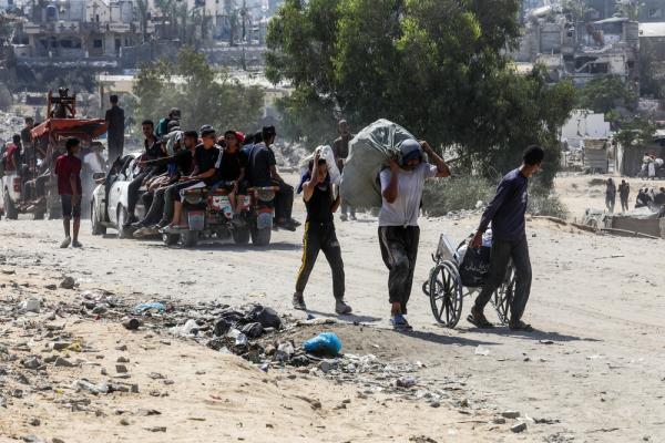 Palestinians carry aid from a GHF distribution site in Gaza.