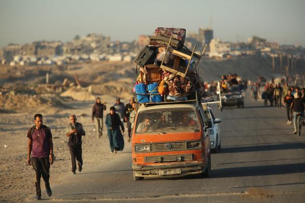 Displaced Palestinians return from southern to northern Gaza, some by foot, and others in crowded cars carrying belongings on the roofs, surrounded by rubble and destruction.