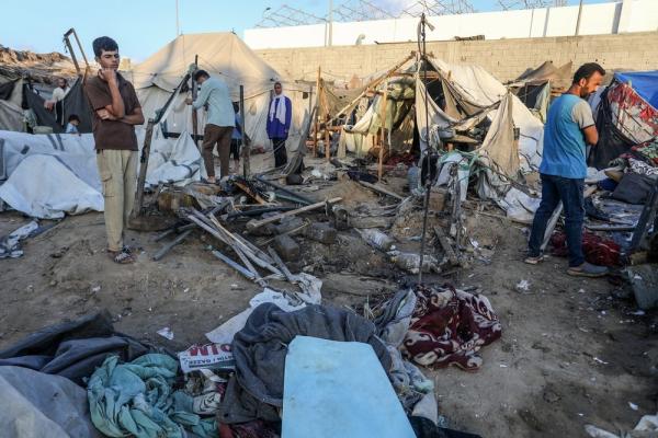 Palestinians inspect the devastation following Israel's airstrike on a tent encampment where displaced Palestinians sheltered.