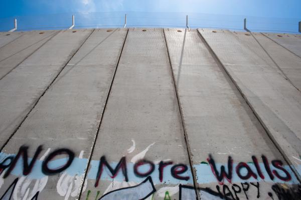 View of Israel's apartheid wall in the West Bank with graffiti that says "No More Walls."