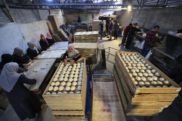 Volunteers in the Bureij camp bake large quantities of bread for displaced Palestinian families during Ramadan.