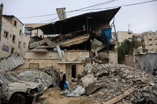 A Palestinian woman walks past the rubble of a destroyed building and car after an Israeli airstrike on July 21, 2026.