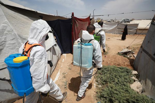 Workers in protective gear carry equipment as they fumigate a makeshift displacement tent camp in Gaza's Bureij refugee camp, to protect displaced Palestinians from rodents and insects.