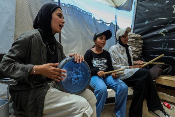 Palestinian girls learn how to play instruments in a music class held at a displacement encampment in GAza.