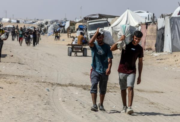 Palestinians walk to and from a GHF distribution site to collect aid.