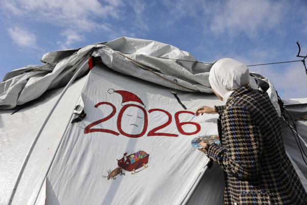 A fifteen-year-old artist, Sarah Saada, paints "2026" on a displacement tent in Beit Lahia in the northern Gaza Strip, in addition to Santa Claus carrying gifts on his reindeer sleigh.