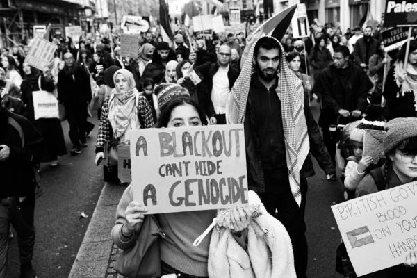 A woman holds a sign that says "A blackout can't hide a genocide" at a protest against Israel's war on Gaza.