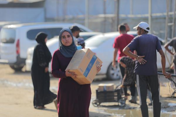 Palestinians carry aid packages distributed by the World Food Programme (WFP) in Al-Zuwaida, near Deir al-Balah in the central Gaza Strip. October 23, 2025.