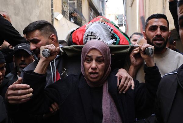 A Palestinian mother leads the funeral procession for her 15 year old son who was killed by the Israeli military during a raid on the Dhisheh refugee camp in the West Bank near the city of Bethlehem. She is surrounded by other mourners in the funeral procession.