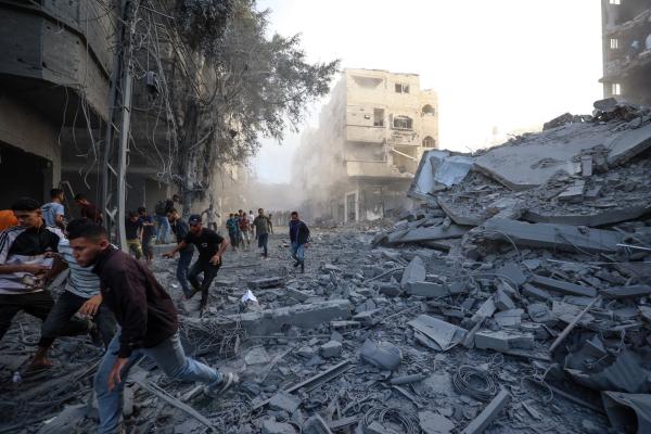 Palestinians flee as Israel bombs a building in the central Gaza Strip's Bureij refugee camp only days after the US-brokered ceasefire agreement. October 19, 2025.