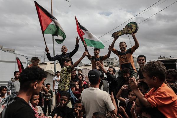 Palestinians in the Nuseirat refugee camp celebrate the announcement of a ceasefire agreement in Gaza. They carry Palestinian flags and a key with illustrations symbolizing the Palestinian right of return. October 9, 2025.