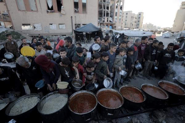 Palestinians wait in line for hot meals distributed from a humanitarian aid organization in Gaza City during Ramadan. February 23, 2026.