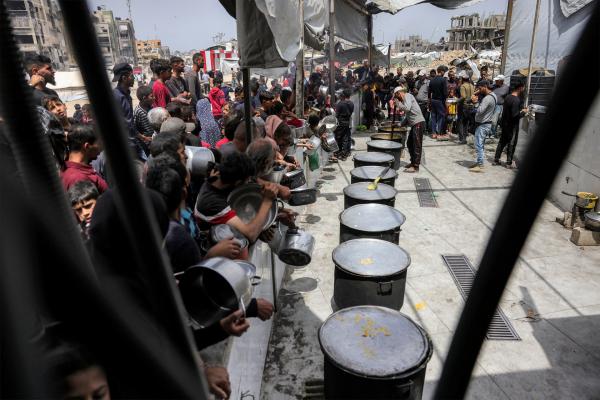 Palestinians wait in line as aid workers prepare to distribute food aid as Israel's forced starvation of Gaza worsens. Beit Lahia, Gaza Strip. April 24, 2025.