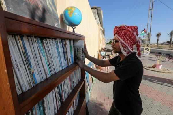 A Palestinian arranges bookshelves at an outdoor cafe in Gaza, July 2021.