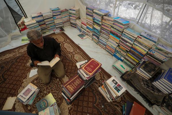 A Palestinian bookseller organizes his collection for sale in Deir al-Balah in the central Gaza Strip, where he lives in displacement. HIs surviving books were recovered under the rubble of his destroyed home in Beit Lahia.