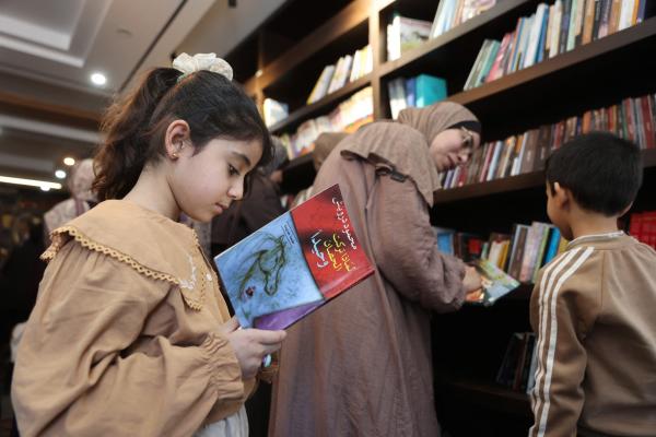 A Palestinian girl reads a copy of Mahmoud Darwish's "Why Did You Leave the Horse Alone?" at the Al-Ankaa (Phoenix) Library in Gaza City. April 21, 2026.