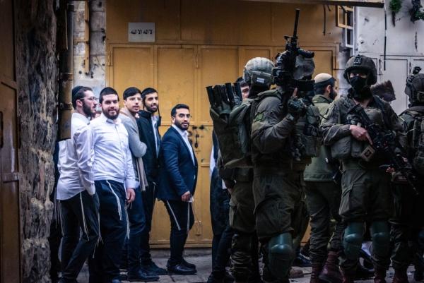Israeli soldiers guard a group of settlers as they walk down the streets of Hebron in the West Bank.