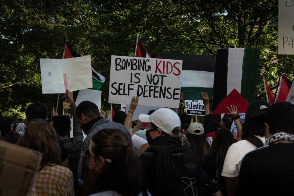 At a rally outside of the Israeli Embassy in Washington DC during the 2021 war on Gaza, a protestor carries a sign that says "BOMBING KIDS IS NOT SELF DEFENSE."