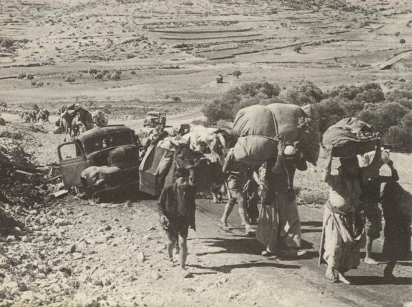 Palestinian refugees are forced to flee by foot from their homes in Palestine as they carry their belongings over their heads, 1948.