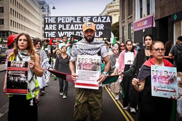 Protestors in London carry signs honoring journalists in Gaza assassinated by Israel.