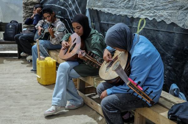 Palestinian girls take a music class, with some playing the guitar and others playing the oud, at the Mayasem Association in Mawasi Khan Younis, Gaza Strip. June 23, 2026.
