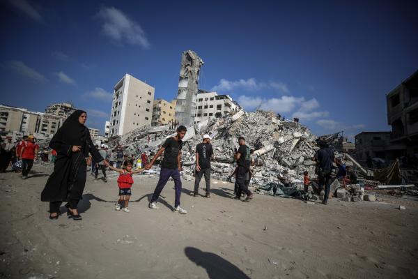 A Palestinian family walks near the rubble of Al-Sousi Tower near the Rimal neighborhood in Gaza City after an Israeli airstrike on September 6, 2025.