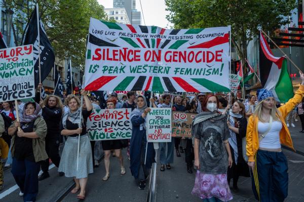 Protestors in Melborne, Australia, hold up signs that say "Where do you give birth if there are no hospitals," "feminist silence is violence," and "LONG LIVE PALESTINIAN WOMEN RESISTING OCCUPATION: SILENCE ON GENOCIDE IS PEAK WESTERN FEMINISM!"