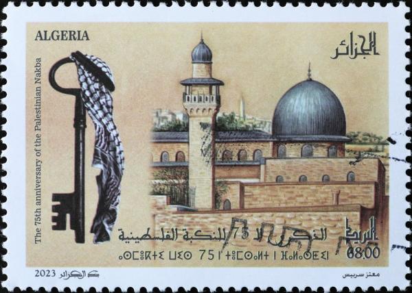 An Algerian postage stamp issued in 2023, commemorating the 75th anniversary of the Palestinian Nakba, by artist Motaz Saryis, contains an illustration of the Qibli Mosque in the Al-Aqsa Mosque compound in Jerusalem beside a key symbolizing the Palestinian right of return, draped in a kuffiyeh. Stamp contains writing in English, Arabic, and the Tamazight (Algerian Amazigh) language.