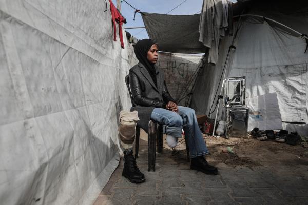 Palestinian schoolteacher Isra Betikh sits outside of her displacement tent in the Nuseirat refugee camp in the central Gaza Strip. She is pictured alongside her prosthetic leg, which he relies on after an Israeli airstrike which killed two of her siblings and forced her leg amputation.