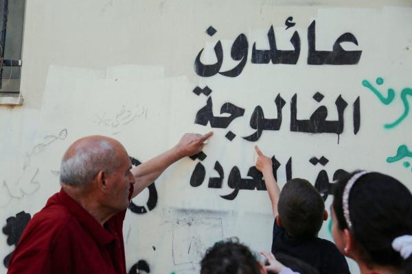 Ahmed Mustafa Al-Najjar, a Palestinian man born in 1943, who has lived in Al-Fawwar camp, south of Hebron, West Bank since 1949, on May 11, 2025 points to a writing on the wall that reads "we will return to al-Falujah, the right of return". He was displaced from the town of Al-Falujah during the 1948 Nakba. He is holding the key to his home, from which he was displaced in the hope of returning. He was able to visit his displaced village and take with him a stone, wheat, and soil.