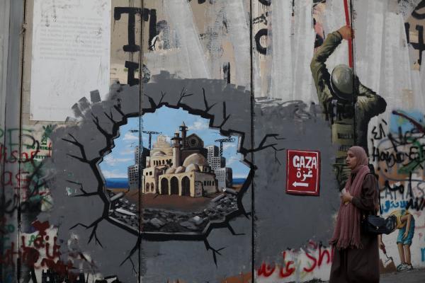  A woman walks past the Bethlehem side of the Separation Wall, where graffiti supporting the reconstruction of the Gaza Strip has been drawn in Bethlehem, West Bank on February 16, 2025. 