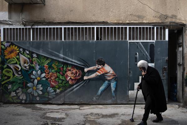 A woman walks in front of a graffiti in the Silwan neighborhood, located south of Al-Aqsa Mosque, as Palestinians are struggling to continue their lives under harsh conditions due to Israeli home demolitions and eviction orders in East Jerusalem on December 31, 2025. 